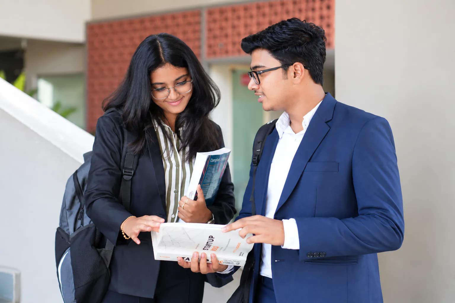 Two management students discussing notes on campus